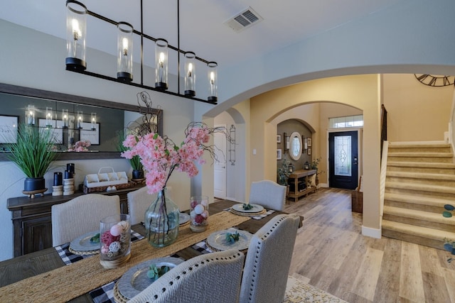 dining area featuring visible vents, baseboards, stairs, wood finished floors, and arched walkways