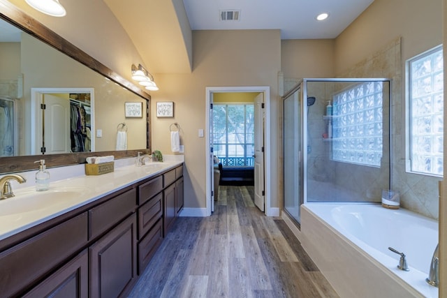 bathroom with vanity, separate shower and tub, a healthy amount of sunlight, and hardwood / wood-style floors