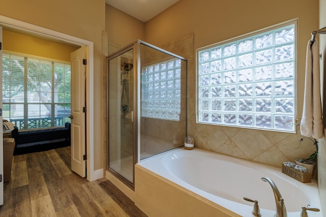 full bath featuring wood finished floors, a stall shower, and a bath