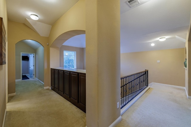 corridor with light colored carpet and lofted ceiling