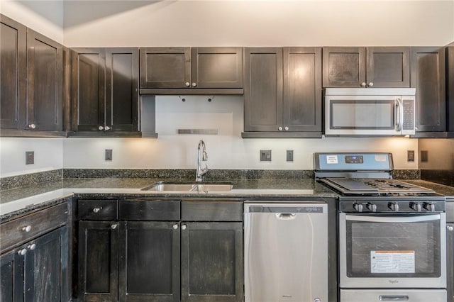 kitchen with appliances with stainless steel finishes, dark brown cabinets, dark stone countertops, and sink