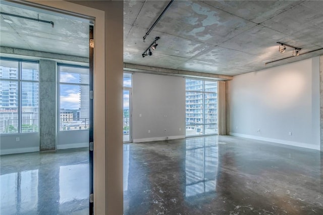 empty room with concrete floors, rail lighting, and a wealth of natural light