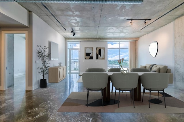 dining room featuring rail lighting and concrete floors