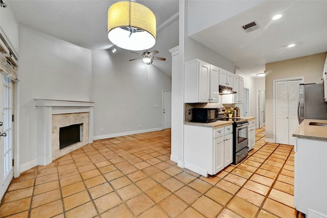 kitchen with ceiling fan, white cabinetry, stainless steel appliances, and a tiled fireplace