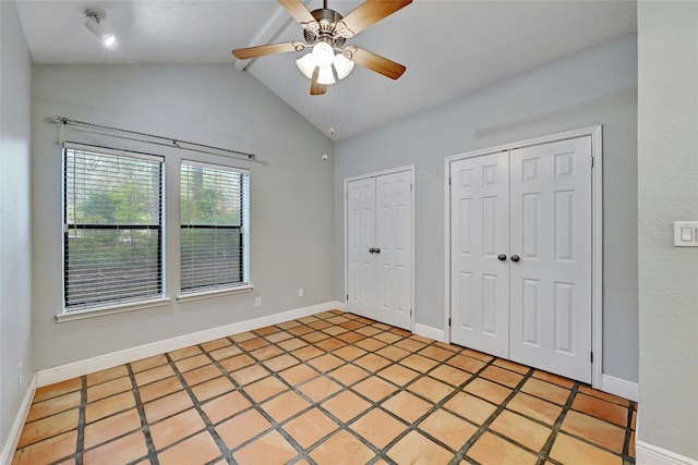 unfurnished bedroom with tile patterned flooring, vaulted ceiling, ceiling fan, and multiple closets