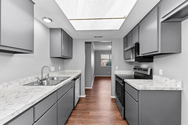 kitchen with appliances with stainless steel finishes, dark hardwood / wood-style flooring, a textured ceiling, and sink