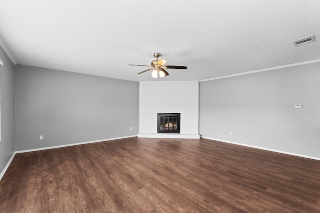 unfurnished living room featuring dark hardwood / wood-style flooring, a textured ceiling, ceiling fan, crown molding, and a fireplace