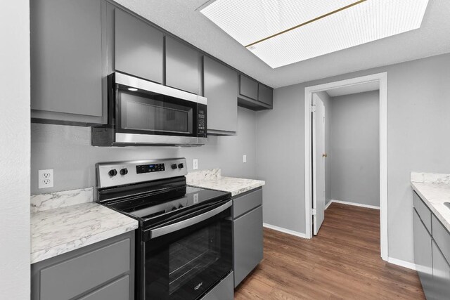 kitchen with gray cabinetry, stainless steel appliances, and dark wood-type flooring