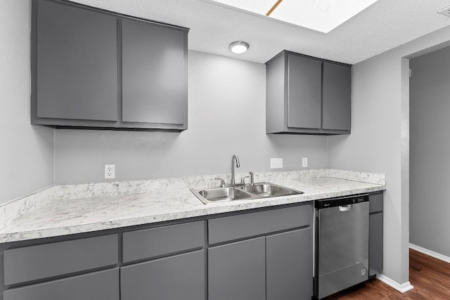 kitchen with gray cabinetry, dishwasher, sink, dark wood-type flooring, and a textured ceiling