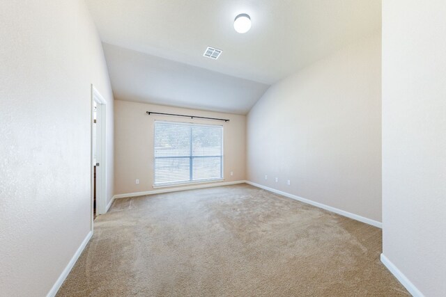 unfurnished room with light colored carpet and lofted ceiling