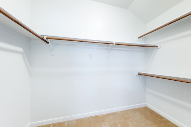 walk in closet featuring light colored carpet and lofted ceiling