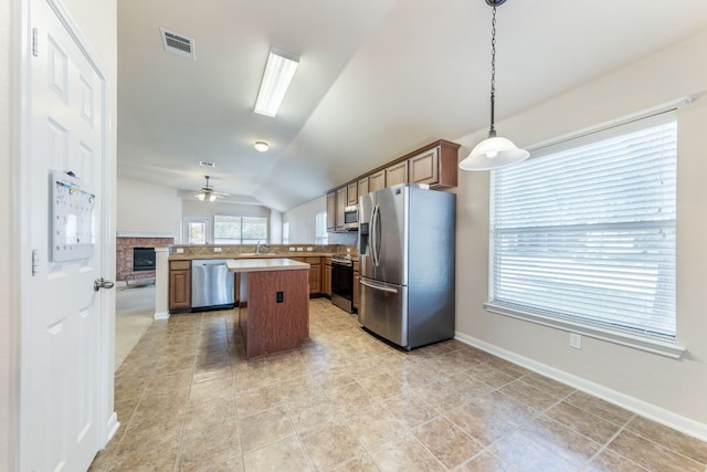 kitchen featuring stainless steel appliances, vaulted ceiling, ceiling fan, a center island, and hanging light fixtures