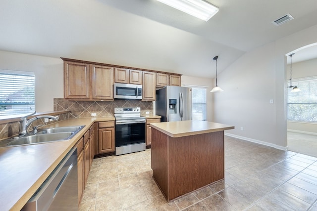 kitchen with plenty of natural light, sink, stainless steel appliances, and vaulted ceiling