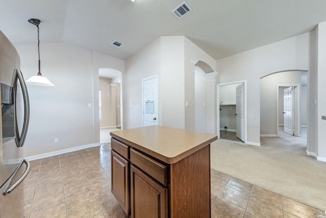 kitchen with pendant lighting, vaulted ceiling, a kitchen island, light colored carpet, and stainless steel fridge with ice dispenser