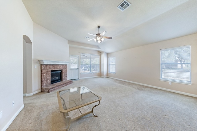 living room featuring ceiling fan, vaulted ceiling, light carpet, and a brick fireplace