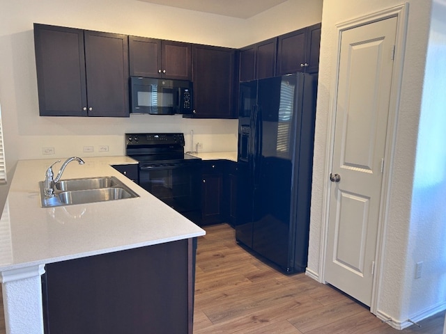 kitchen featuring black appliances, light wood-type flooring, kitchen peninsula, and sink