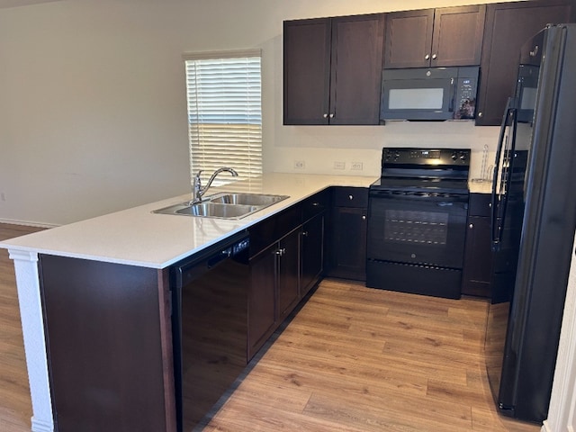 kitchen with black appliances, sink, light hardwood / wood-style flooring, dark brown cabinets, and kitchen peninsula