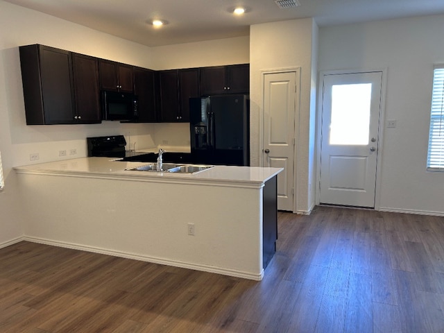 kitchen with black appliances, sink, kitchen peninsula, and dark wood-type flooring