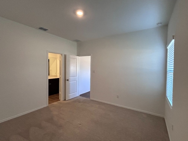 unfurnished bedroom featuring carpet flooring and ensuite bathroom