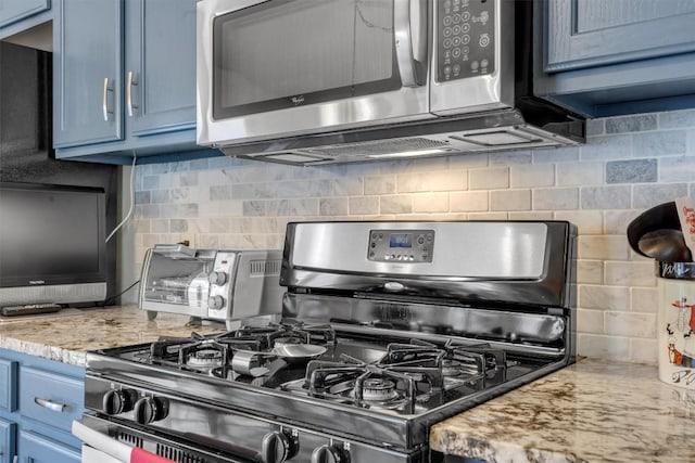 kitchen featuring decorative backsplash, black gas stove, light stone counters, and blue cabinetry