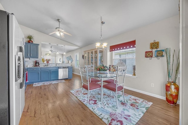 dining space featuring ceiling fan with notable chandelier, lofted ceiling, and light wood-type flooring