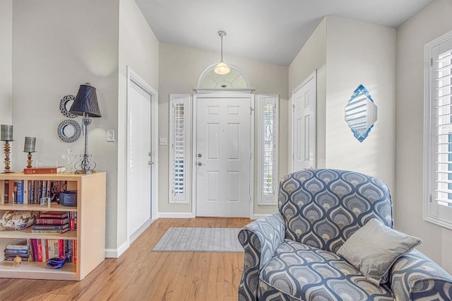 foyer with plenty of natural light, lofted ceiling, and hardwood / wood-style flooring