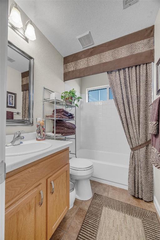 full bathroom featuring shower / bathtub combination with curtain, tile patterned flooring, a textured ceiling, toilet, and vanity