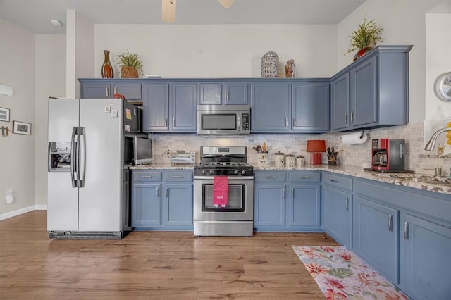 kitchen featuring light stone countertops, sink, light hardwood / wood-style floors, and appliances with stainless steel finishes