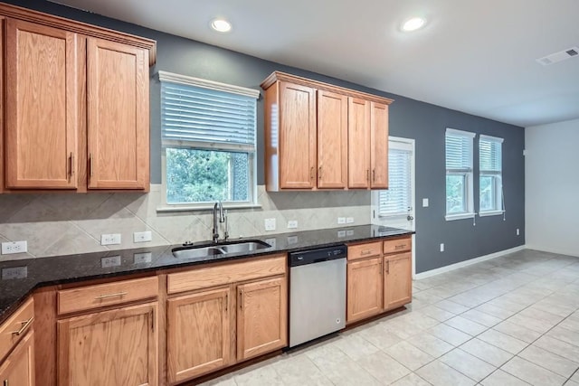 kitchen with sink, light tile patterned floors, dishwasher, dark stone counters, and decorative backsplash