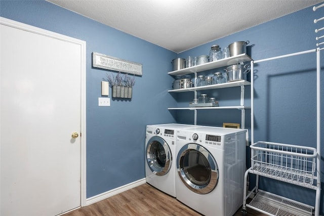 laundry area with washer and clothes dryer, a textured ceiling, and hardwood / wood-style flooring