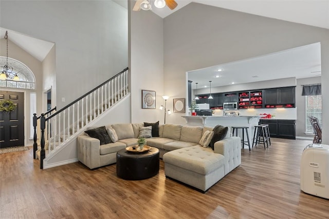 living room with ceiling fan, high vaulted ceiling, and wood-type flooring