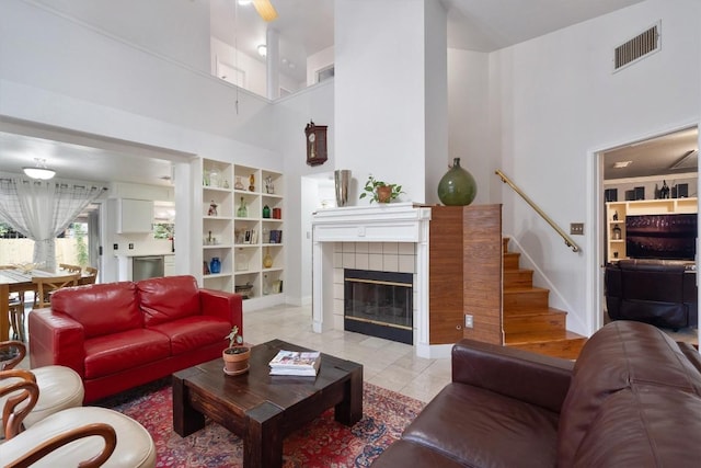 12809 Meehan Dr, Austin, TX 78727 - living area with a fireplace, a towering ceiling, stairs, built in shelves, and light tile patterned flooring