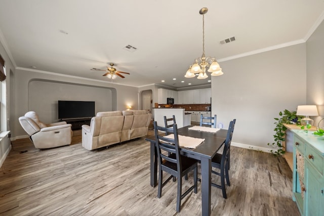 dining space with light hardwood / wood-style flooring, ceiling fan with notable chandelier, and ornamental molding