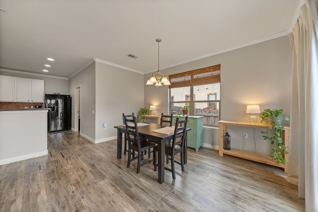 dining space featuring ornamental molding, a notable chandelier, and light wood-type flooring