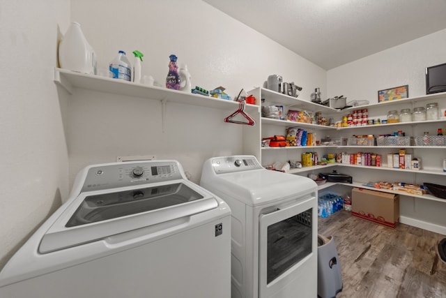 clothes washing area with washing machine and clothes dryer and light hardwood / wood-style floors