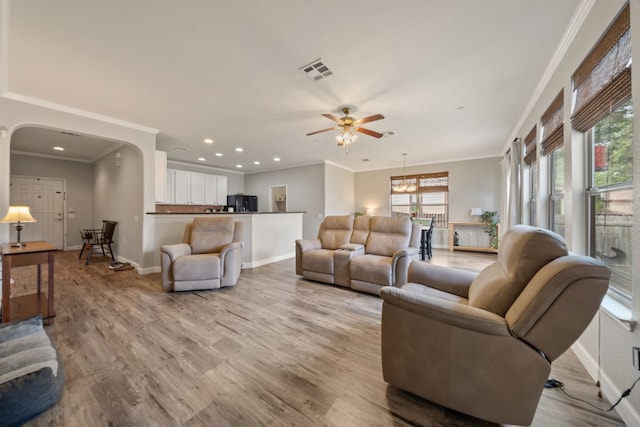 living room featuring ceiling fan with notable chandelier, light wood-type flooring, and ornamental molding