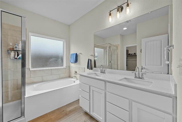 bathroom featuring plus walk in shower, wood-type flooring, and vanity