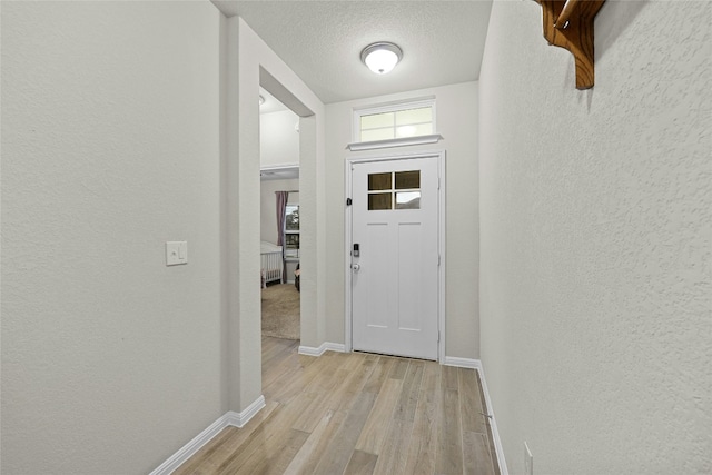 foyer entrance featuring a textured ceiling and light hardwood / wood-style floors