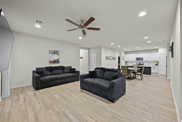 living room with ceiling fan and light wood-type flooring