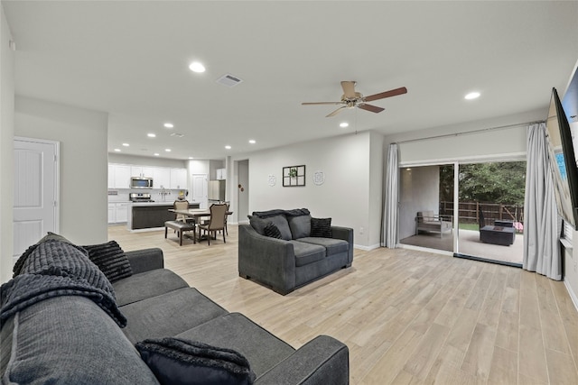 living room with ceiling fan and light hardwood / wood-style flooring