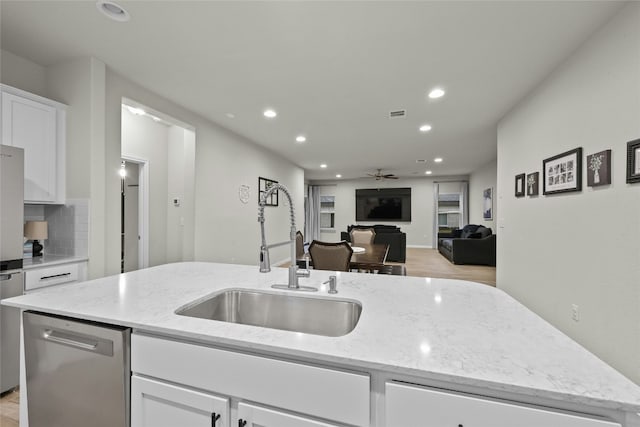 kitchen featuring a center island with sink, sink, light stone countertops, and stainless steel appliances