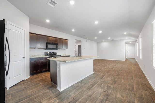 kitchen with dark brown cabinetry, light stone counters, dark hardwood / wood-style floors, a kitchen island with sink, and black appliances