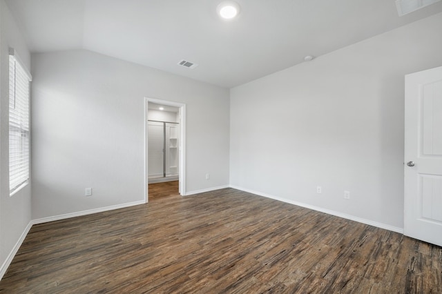 empty room with dark hardwood / wood-style flooring and vaulted ceiling