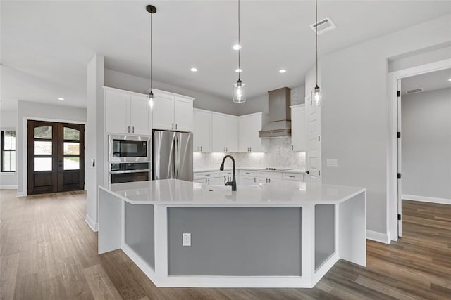 kitchen featuring premium range hood, white cabinetry, stainless steel appliances, and a large island