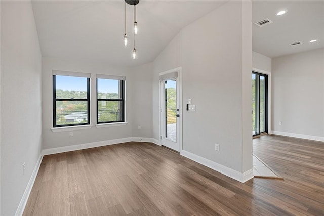 spare room with hardwood / wood-style floors and vaulted ceiling