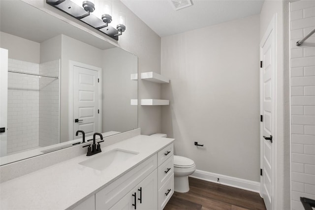 bathroom with vanity, hardwood / wood-style flooring, toilet, and a tile shower