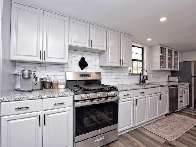 kitchen featuring white cabinetry, sink, stainless steel appliances, and wood-type flooring