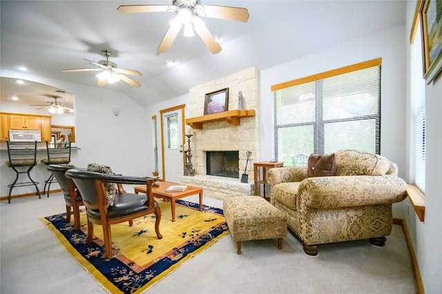 living room with carpet flooring, vaulted ceiling, and a stone fireplace