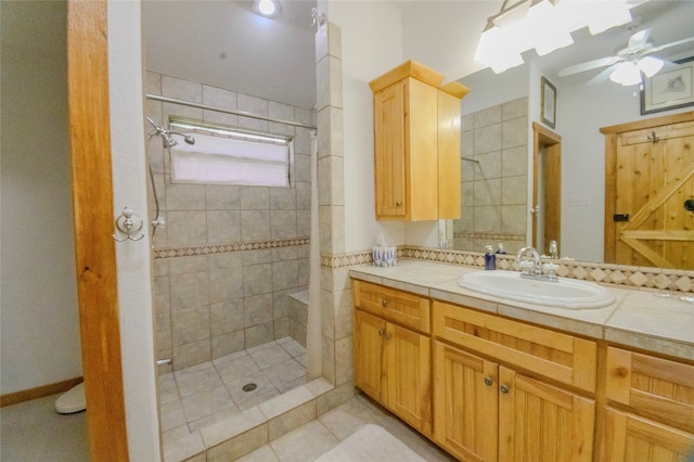 bathroom featuring a tile shower, ceiling fan, tile patterned flooring, and vanity