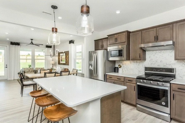 kitchen with a kitchen island, hanging light fixtures, and appliances with stainless steel finishes